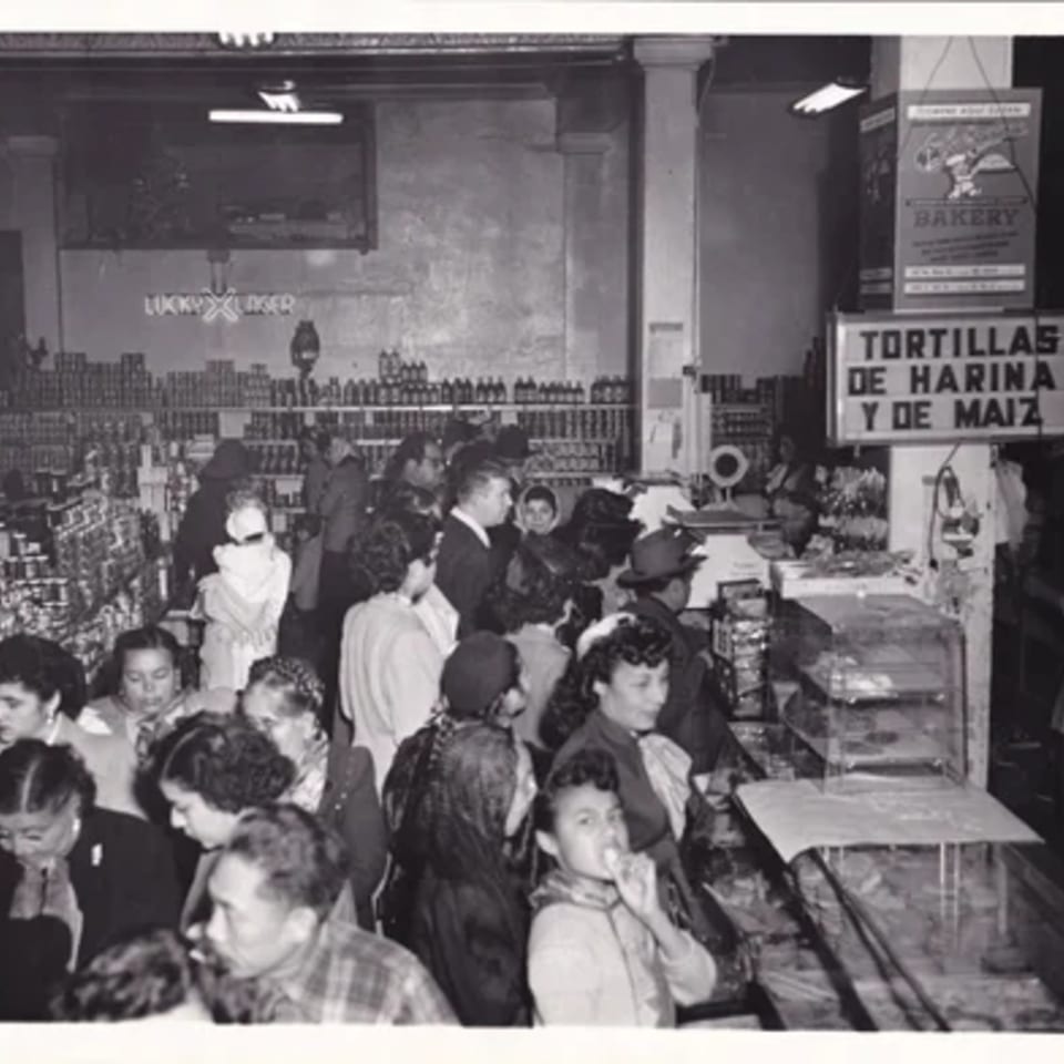 Black and white photo of a crowded La Luz del Día restaurant with people waiting in line.