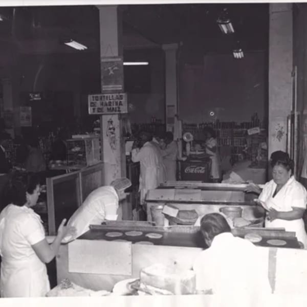 Black and white photo of women making tortillas in a busy Mexican restaurant kitchen.