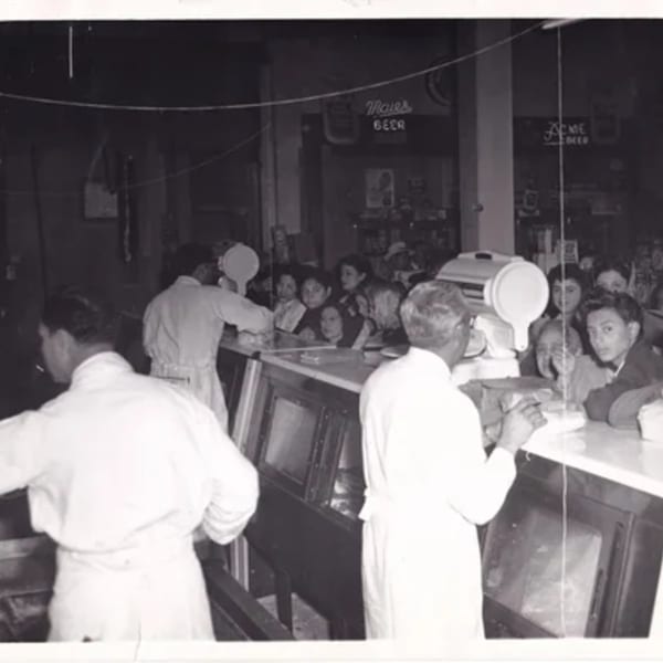 Black and white photo of La Luz del Día restaurant with staff serving customers at a counter.