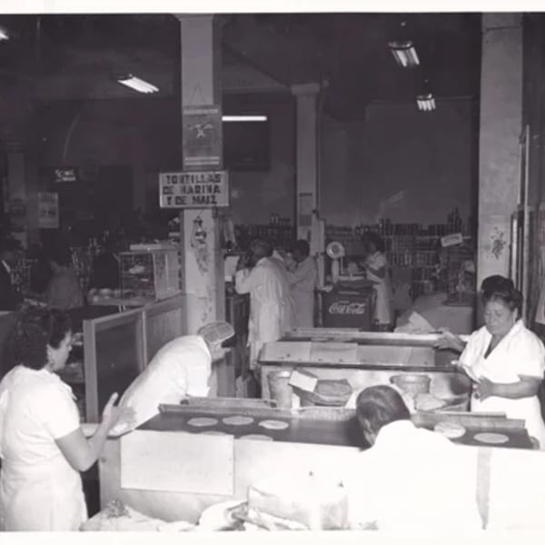 Black and white photo of women making tortillas in a busy La Luz del Día kitchen.