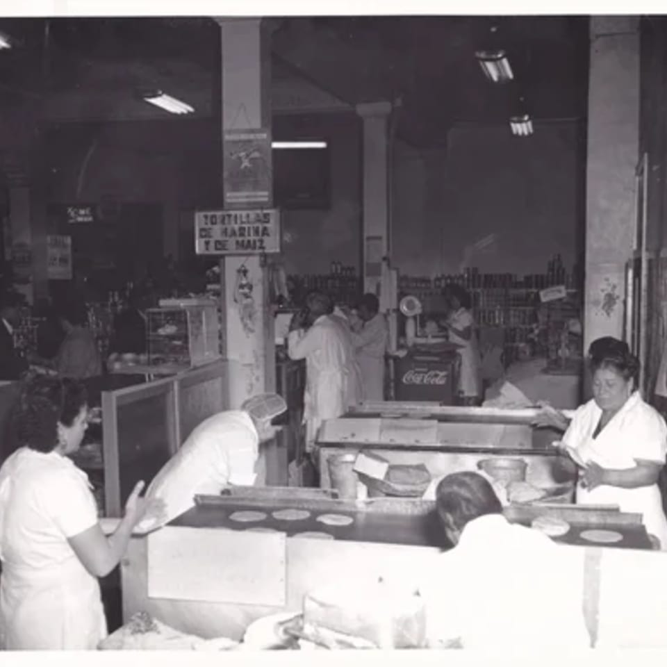 Black and white photo of women making tortillas in a busy La Luz del Día kitchen.