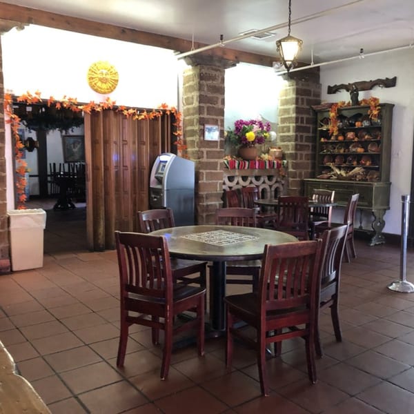 Interior of La Luz del Día Restaurant with tables, chairs, brick pillars, and Mexican-themed decor.