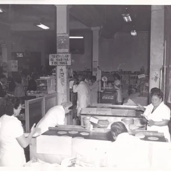 Black and white photo of women making tortillas in a busy Mexican restaurant kitchen.