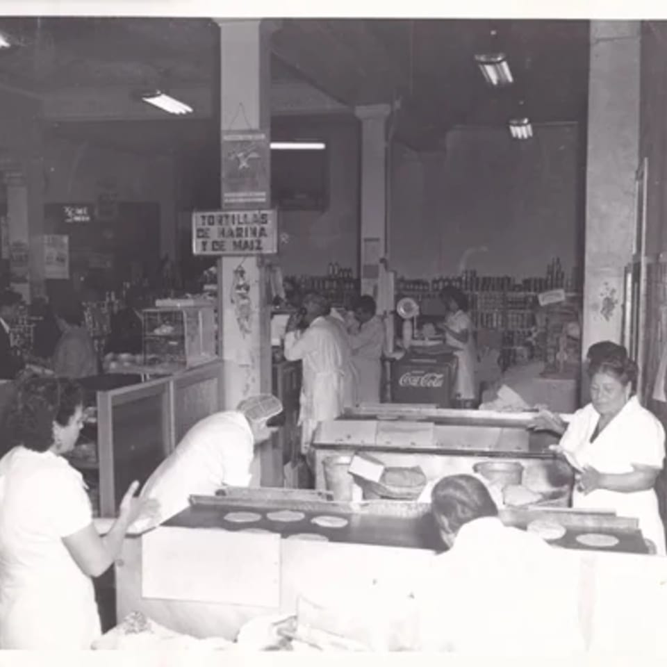 Black and white photo of women making tortillas in a busy Mexican restaurant kitchen.